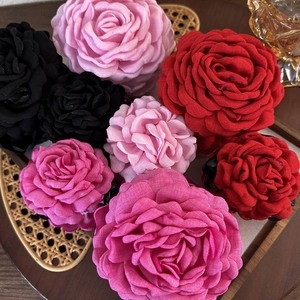 Elegante große Stoff-Rosen-Haarklammern in verschiedenen Vintage-Farben auf Holztablett