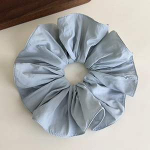 Close-up of light blue ruffled oversized scrunchie with soft pleated chiffon fabric