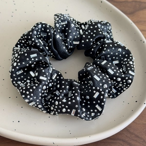 Dettaglio di elastico in raso nero con strass scintillanti tondi e rettangolari