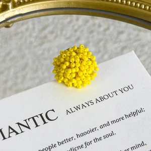 Macro view of handmade yellow beaded floral charm for clogs with high textural detail