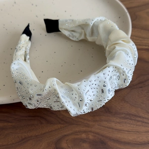 Dettaglio del cerchietto in seta bianco crema con strass scintillanti e cristalli lucidi