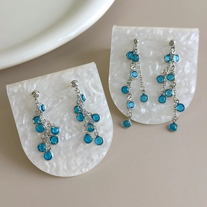 Detailed macro view of cascading long blue crystal fringe earrings with silver chain tassels