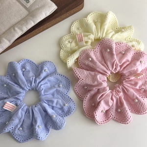Détail de trois chouchous en dentelle pastel avec perles blanches et étiquettes faites main