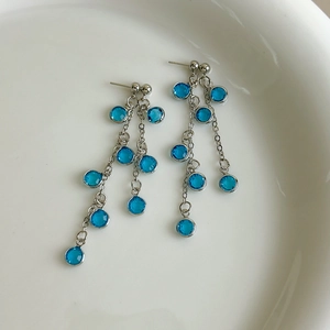 Detailed view of silver chain earrings with multi-layered deep blue crystal grapes