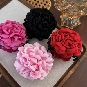 Detail von vier großen Stoffblumen-Haarklammern in Rosa, Schwarz, Rot und Hellrosa
