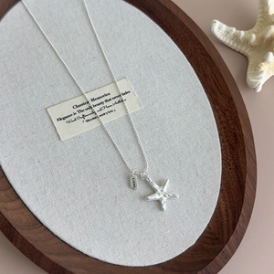 Detailed close-up of a silver starfish pendant and lucky tag on a summer bead necklace