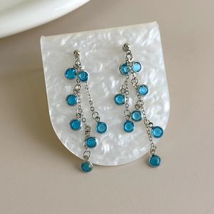 Detailed macro view of blue crystal grape cluster tassel earrings with silver chains