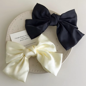 Close-up of elegant black and cream satin bow hair clips on a decorative ceramic plate