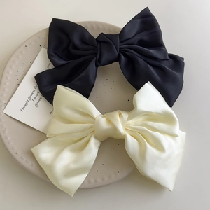 Detailed macro view of large cream and black satin bow clips on a ceramic plate