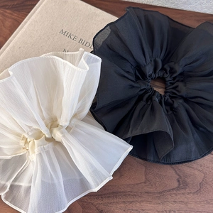 Chouchous oversize noir et blanc en organza avec volants plissés sur un livre