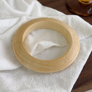 Gros plan d'un bracelet large en résine avec texture grain de bois sur tissu