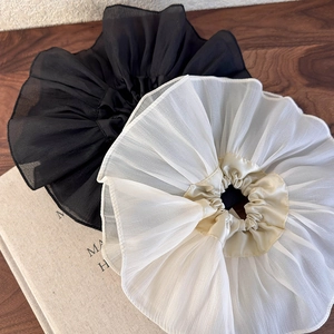 Détail de chouchous surdimensionnés en mousseline plissée noire et beige aux bords fins