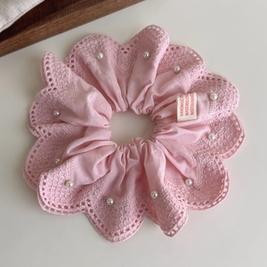 Détail d'un chouchou en dentelle rose avec perles et étiquette Made in Seoul