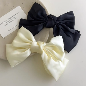 Close-up of large black and cream satin bow hair clips on an elegant ceramic plate