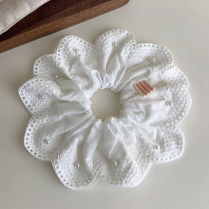 Gros plan détaillé du chouchou en dentelle blanche avec perles élégantes et étiquette Seoul