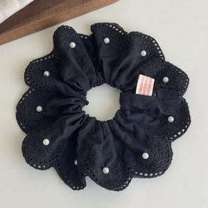 Gros plan sur chouchou en dentelle noire avec perles blanches et étiquette fait main