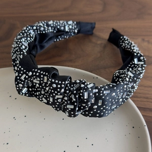 Dettaglio di un cerchietto plissettato nero con decorazioni in strass scintillanti