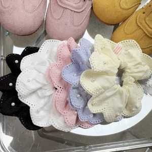 Détail de chouchous en dentelle colorée avec perles blanches en noir, blanc, rose et lilas