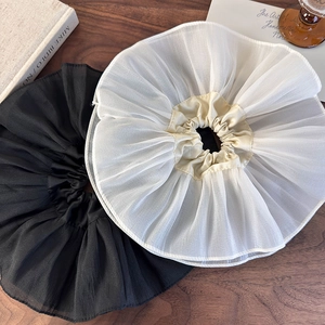 Détail de chouchous en organza surdimensionnés noir et crème sur table en bois