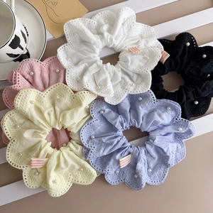 Gros plan sur des chouchous en dentelle à perles de couleurs blanc, noir, rose, jaune et bleu