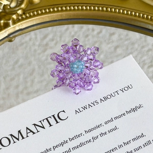 Macro detail of handmade purple beaded flower charm with crystal facets on card