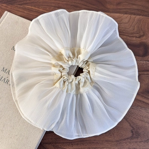 Détail d'un chouchou élégant en organza crème avec une texture de tissu à volants