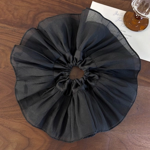 Gros plan d'un grand chouchou plissé noir en organza transparent sur bois