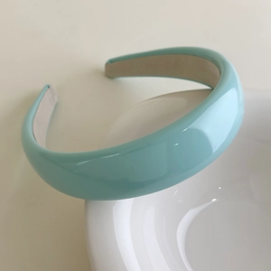 Detail of light blue patent leather headband showing glossy finish and beige anti-slip lining