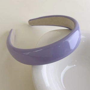 Detail view of purple glossy patent leather padded headband with beige suede lining
