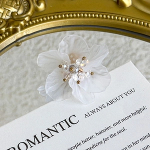 Macro view of white floral shoe charm with crystal center and elegant gold hardware