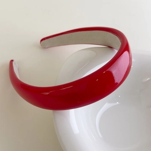 Detail of red shiny patent leather headband with anti-slip inner lining on white bowl
