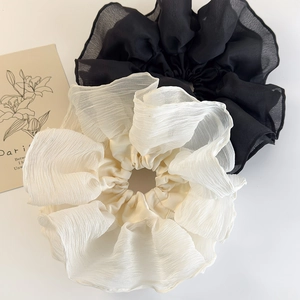 Detail view of large pleated chiffon scrunchies in black and beige with wavy lace design