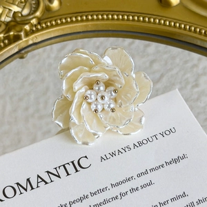 Close-up of floral shoe charm with cream glaze petals and elegant pearl center details