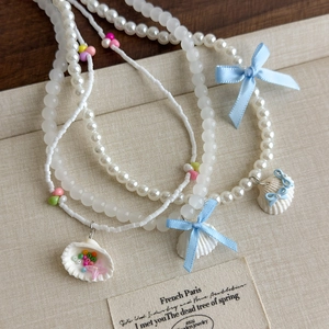 Collier de perles style océan avec nœud en ruban bleu et pendentif coquillage étoilé