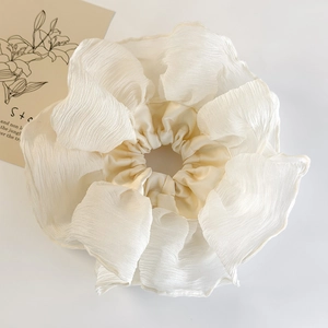 Macro shot of oversized creamy white ruffled scrunchie with soft chiffon pleat texture