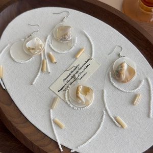 Elegant long shell tassel earrings with vintage beads on a rustic wooden tray