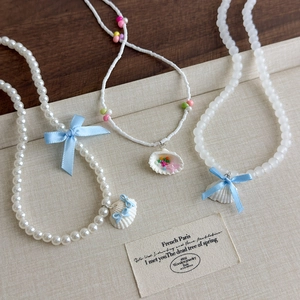 Lot de trois colliers en perles style océan avec pendentifs coquillages et nœuds bleus