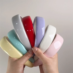 Macro shot showing seven colors of glossy patent leather sponge headbands held in hand