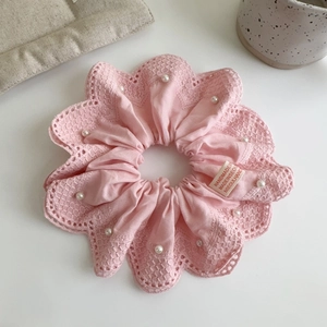 Détail d'un chouchou en dentelle rose avec perles et étiquette artisanale de style coréen