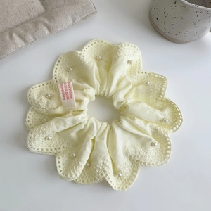 Détail du chouchou en dentelle jaune clair avec perles blanches et étiquette fait main