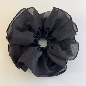 Detailed view of the layered black organza fabric texture on a large scrunchie