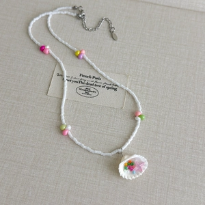 Détail du collier de perles avec pendentif coquillage et breloque étoile rose