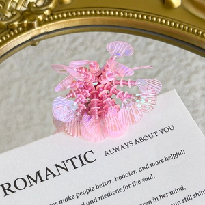 Close-up of pink iridescent petal shoe charm with shiny beads on a mirror surface