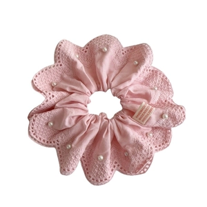 Détail d'un chouchou rose en dentelle avec perles blanches et étiquette fait main