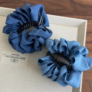 Detailed close-up of dark and light blue denim fabric hair claws in a tray