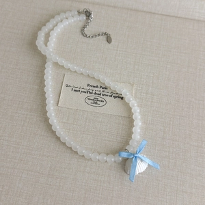 Détail du collier de perles avec pendentif coquillage et ruban bleu clair délicat