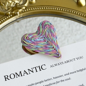 Macro detail of colorful woven heart charms with golden brackets for DIY shoe decoration
