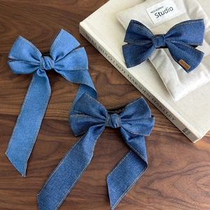 Detailed view of denim bow hair clips with hand-stitched seams and micro handmade label