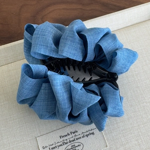 Close-up of the textured denim fabric and pleated design on this oversized blue hair claw clip