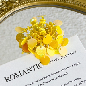 Detailed macro view of sparkling yellow sequin beads and charms for DIY footwear decoration